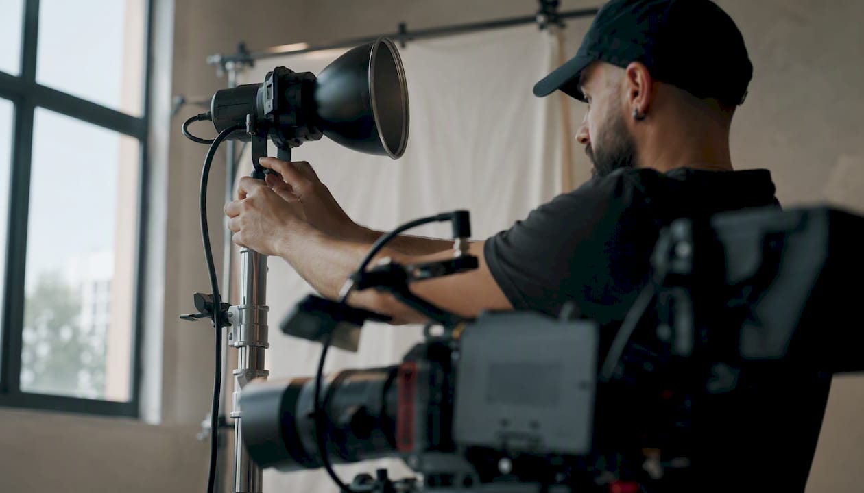 Hands adjusting professional video camera and lighting