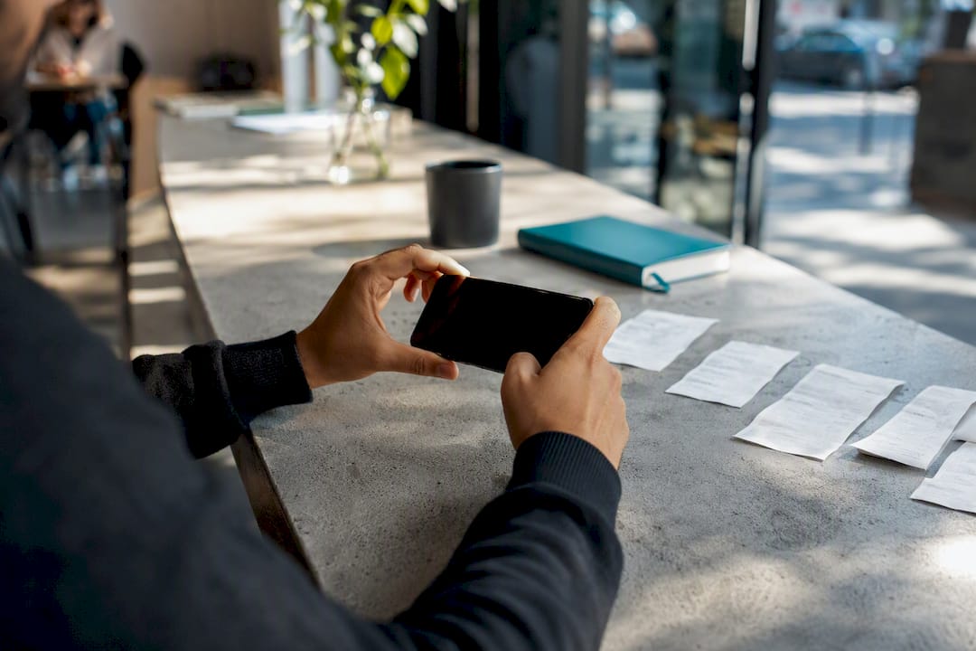 Hands photographing receipts with smartphone