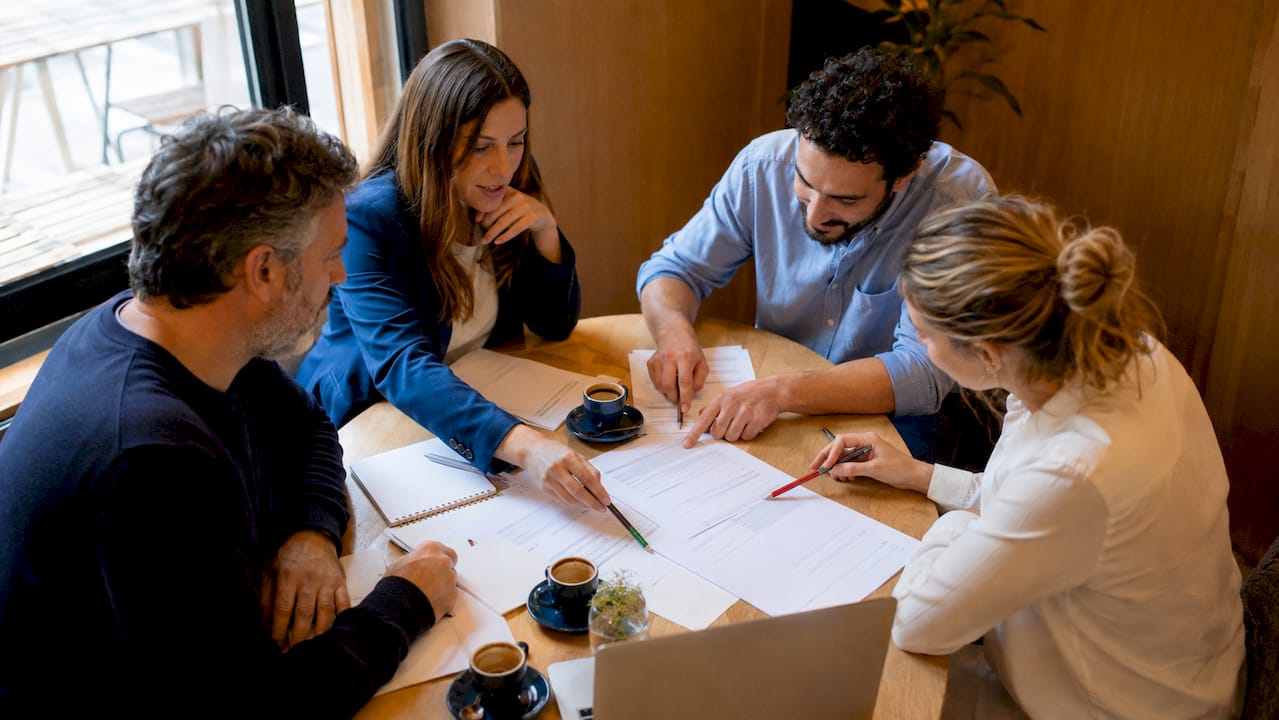 Il team si confronta sui documenti necessari per la certificazione ISO durante una riunione.