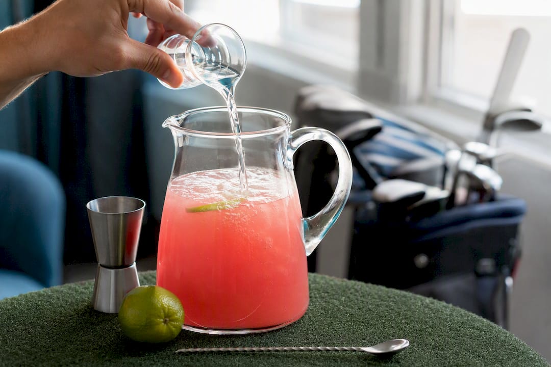 Adding measured water to cocktail batch in pitcher