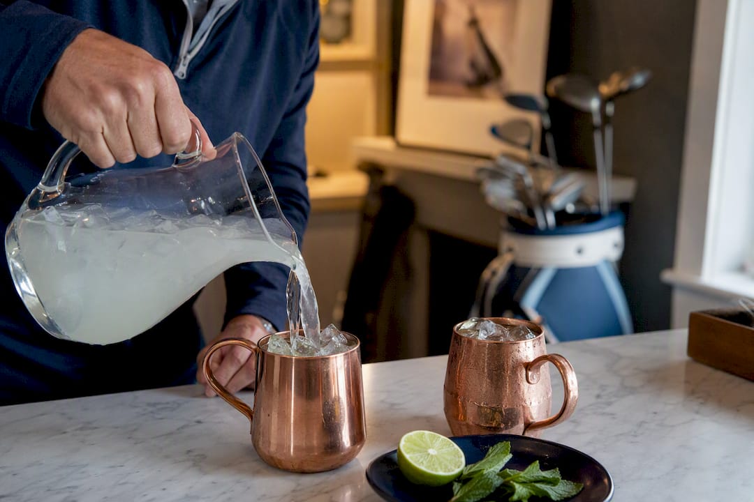 Pouring vodka-lime mix into copper mugs