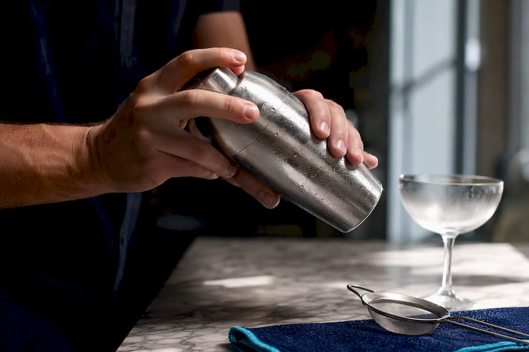 Hands shaking chilled cocktail shaker