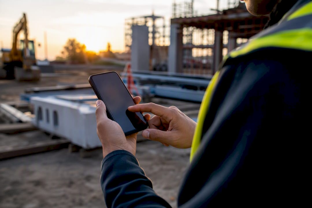 Hands holding smartphone at job site