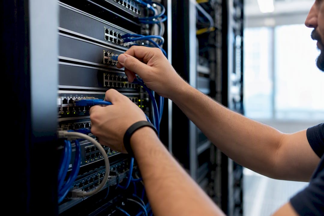 Hands connecting Ethernet cables to network switch