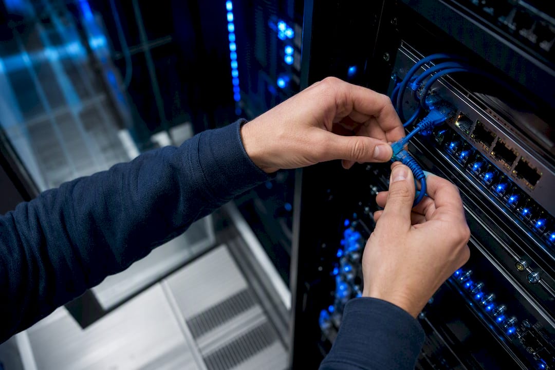Hands unplugging Ethernet cable in server room