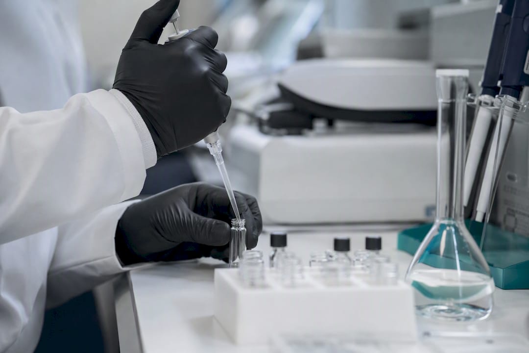 Hands dosing peptide nanoparticles in cancer research lab
