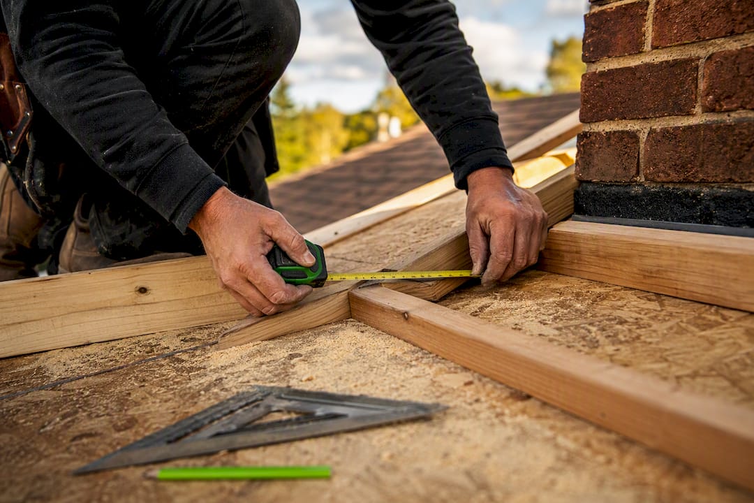 Hands framing chimney cricket on wooden roof