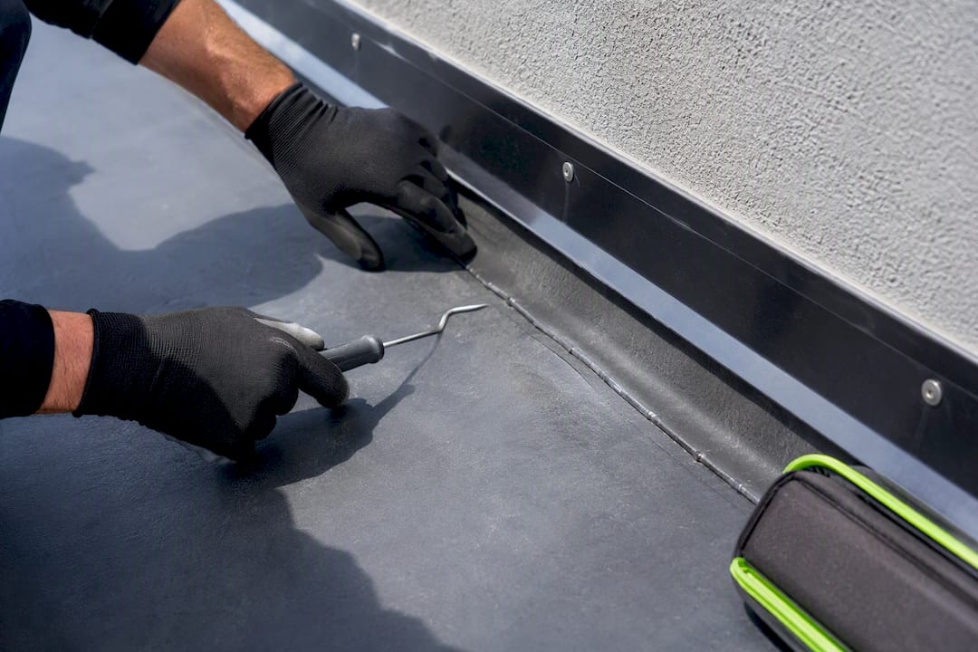 Technician inspecting flat roof flashing seam