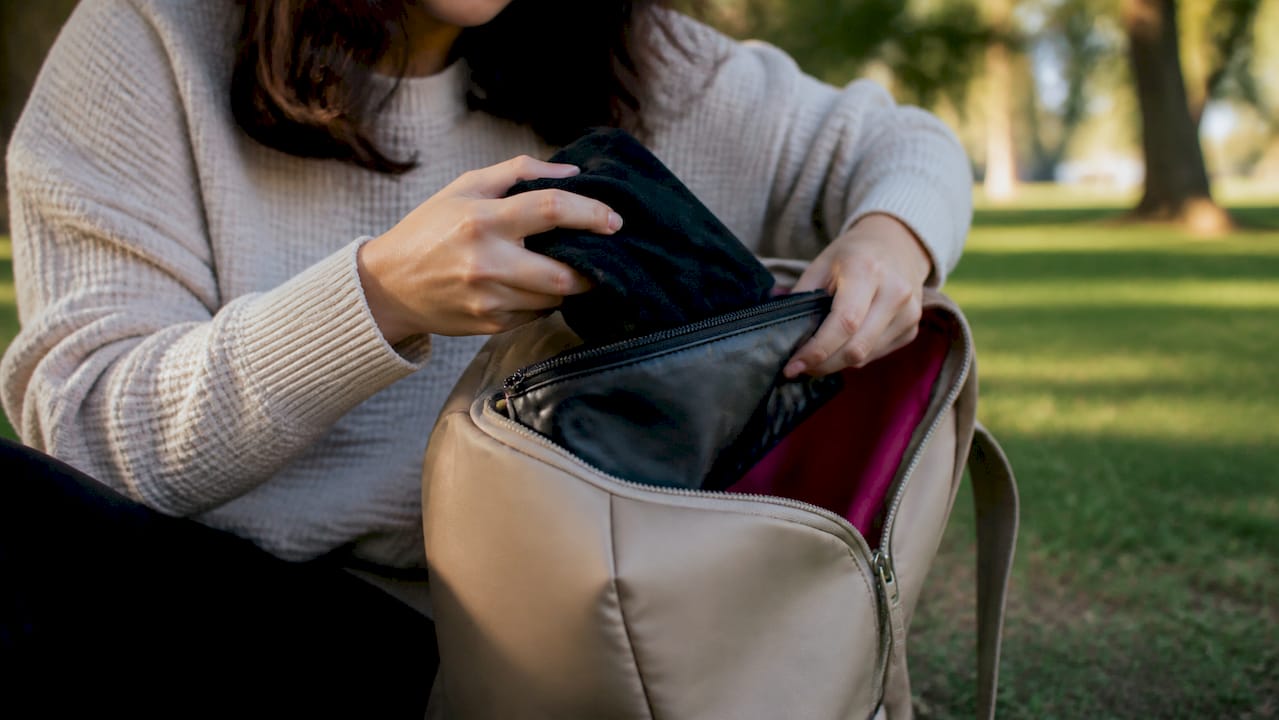 Hands packing period underwear into wet bag