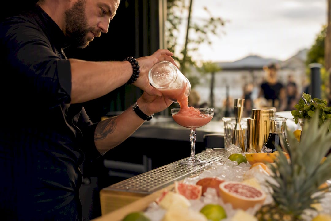 Barkeeper schenkt bunten Slush-Cocktail ein