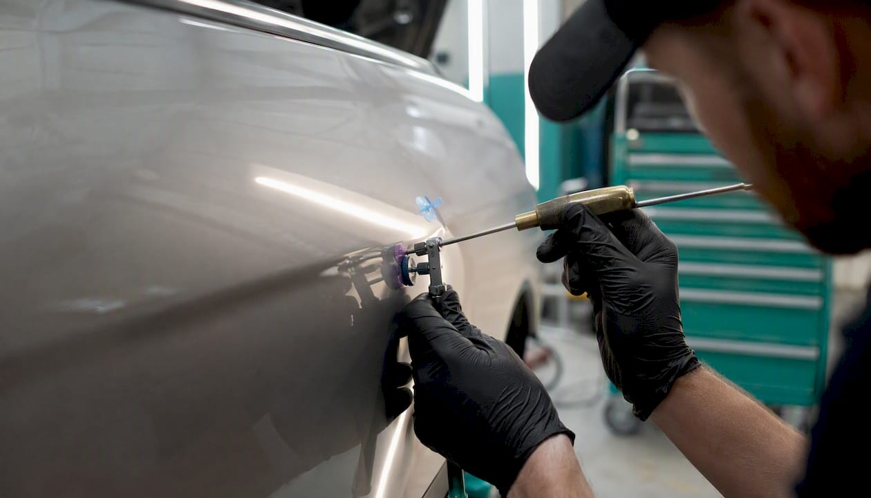 Technician hands repairing dent on aluminum panel