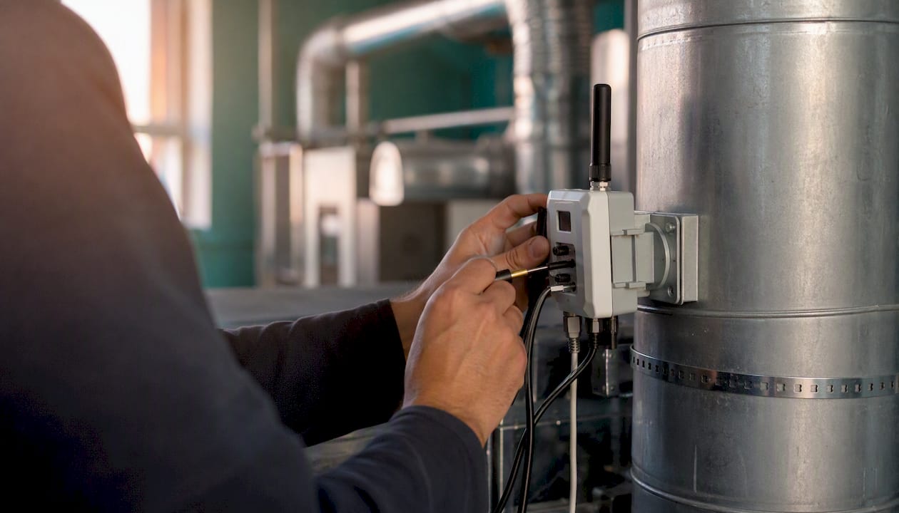 Especialista realiza la calibración de un sensor IoT dentro de la cabina de pintura.