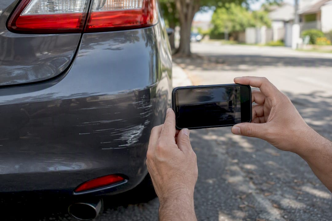 Car owner taking close-up photo of vehicle paint damage