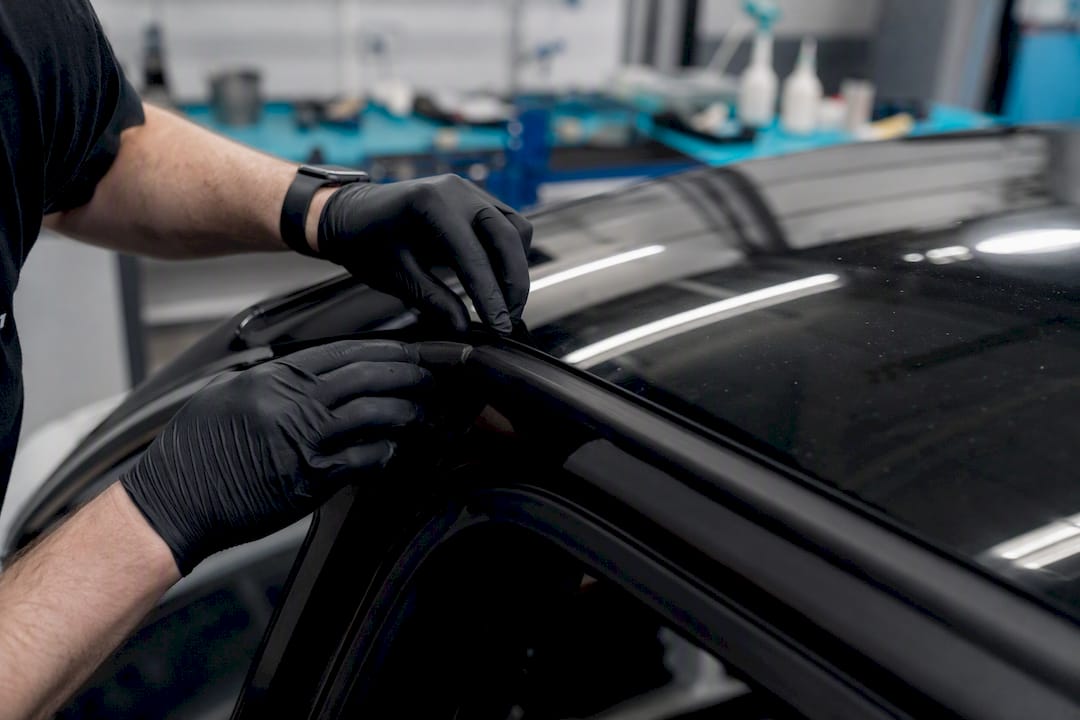 Technician inspecting Tesla glass roof edge close-up