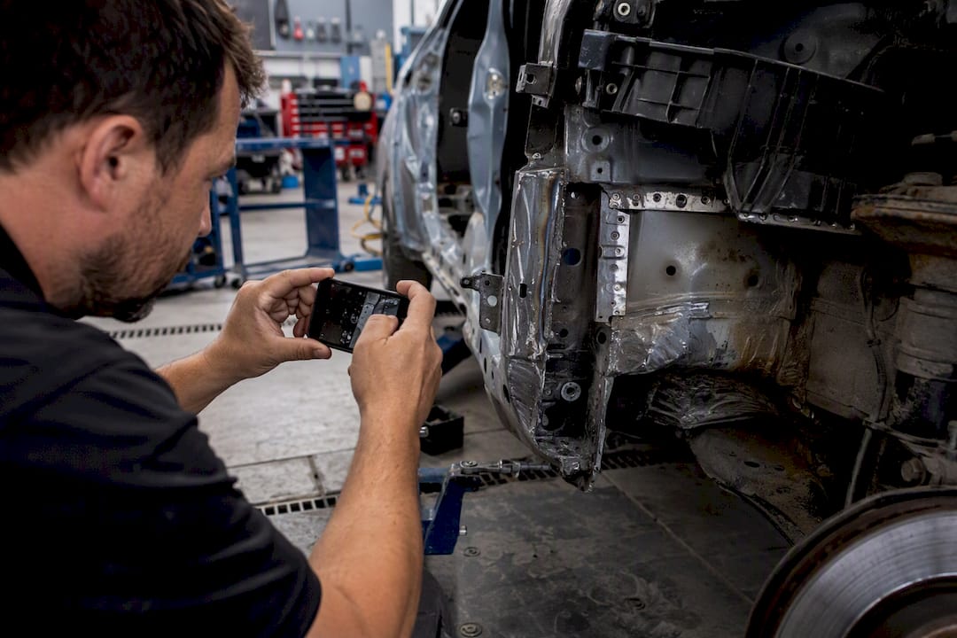 Hands photographing vehicle frame damage