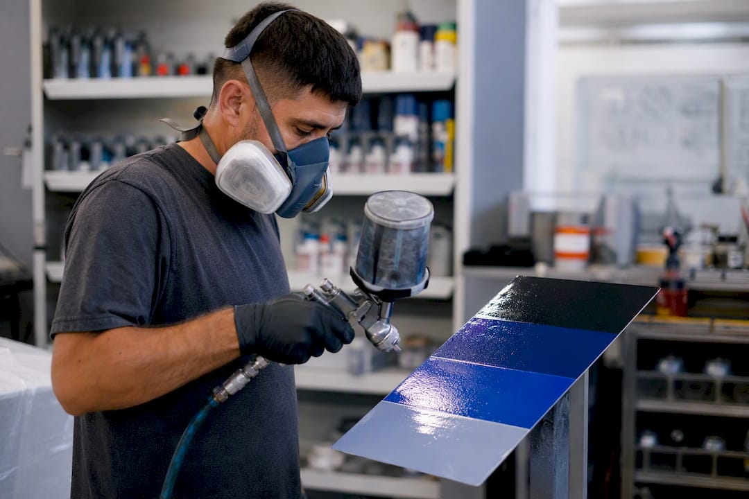 Técnico aplicando una muestra de pintura sobre un panel de prueba