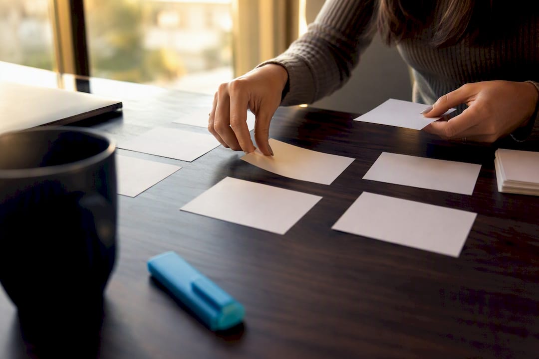 Hands arranging interview framework cards on desk