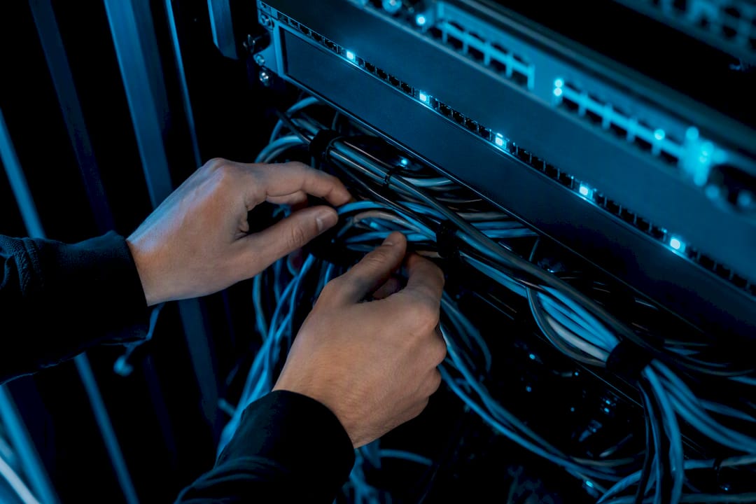 Hands managing cables under server rack