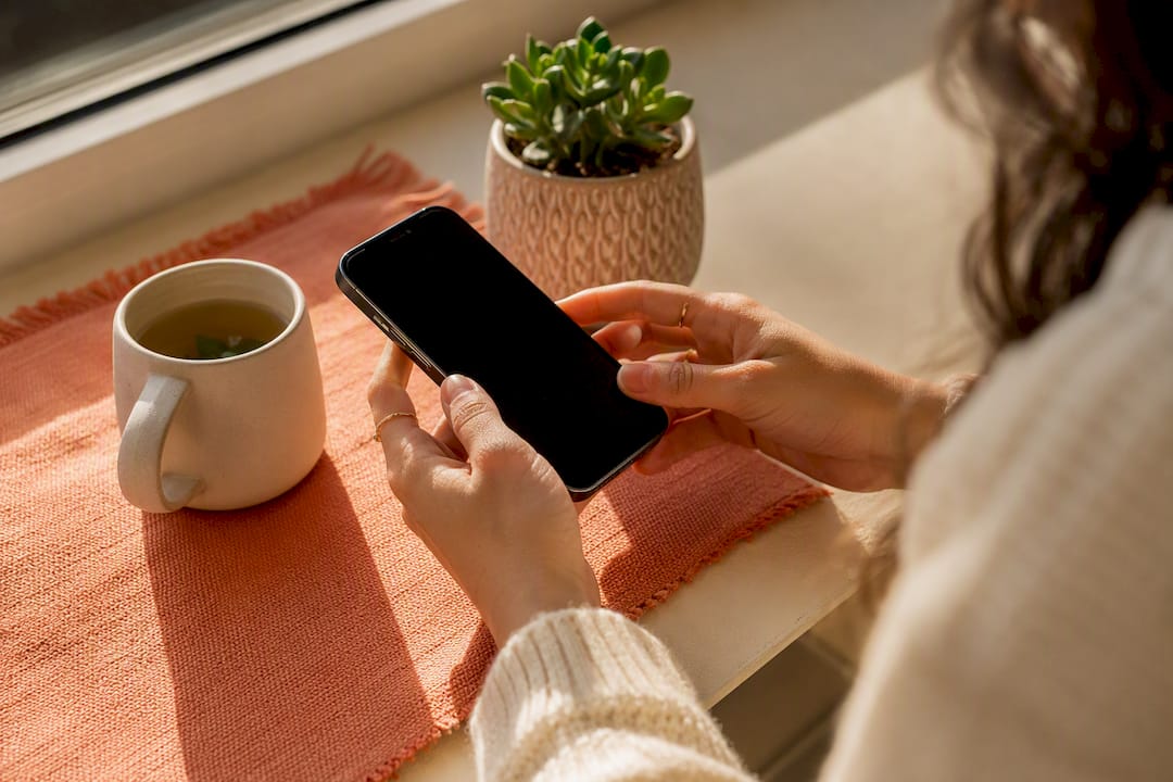 Hands inspecting smartphone on table
