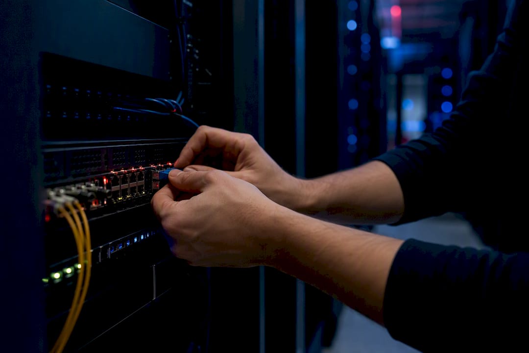Hands connecting fiber optic cables in server room