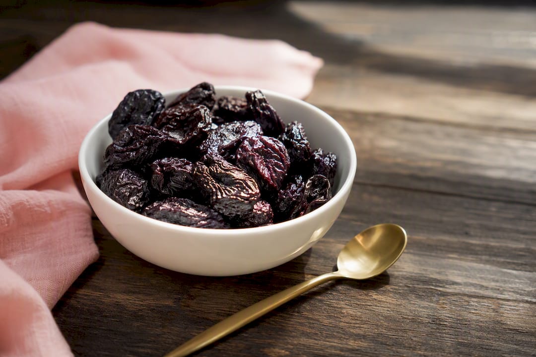 Dried prunes in wooden bowl close-up