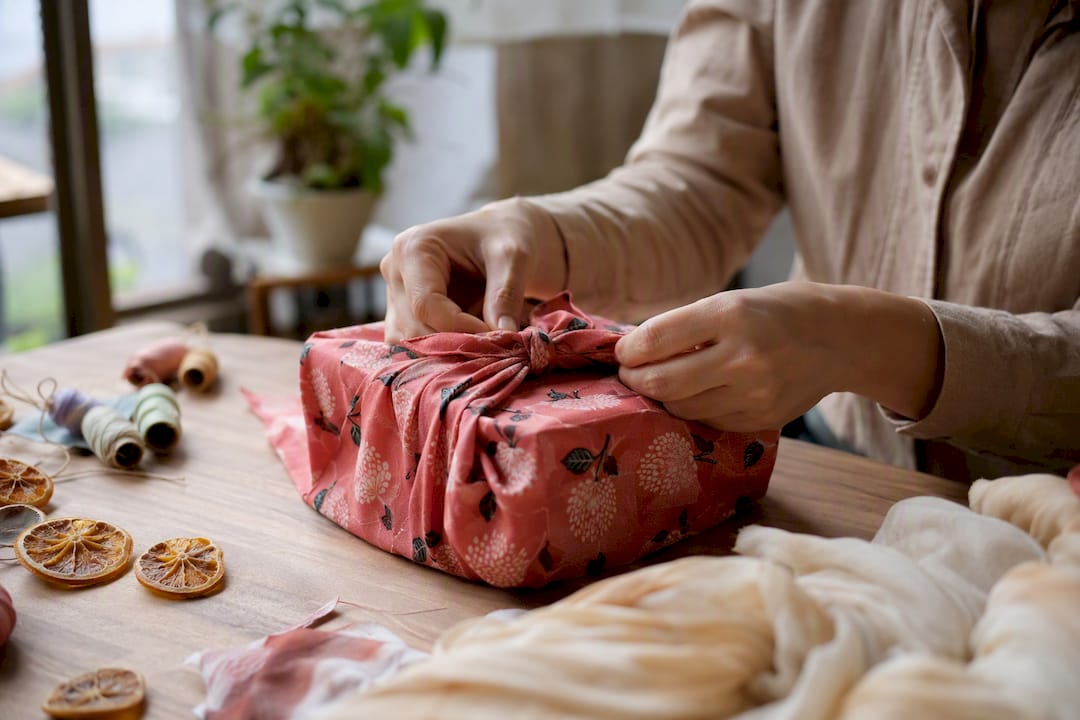 Hands folding fabric wrap for gift