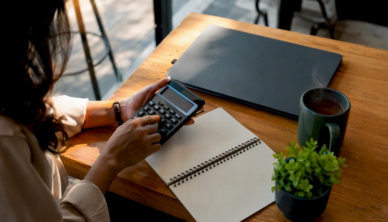Hands using calculator with notebook and coffee
