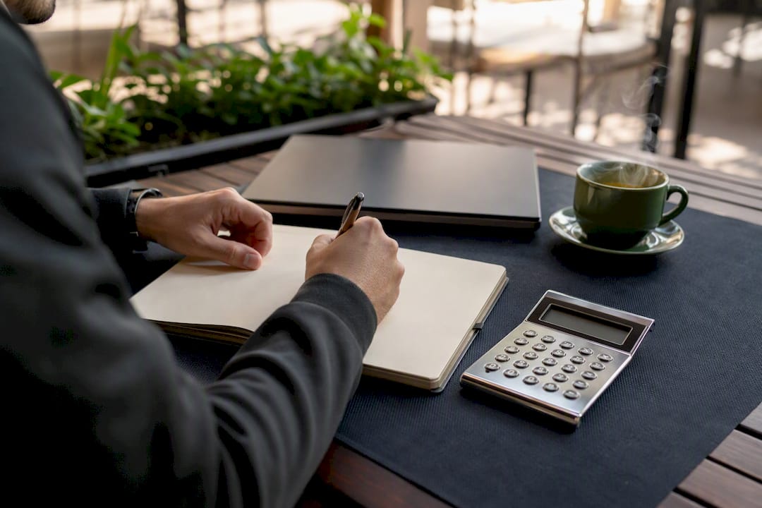 Hands writing risk management notes at trading desk