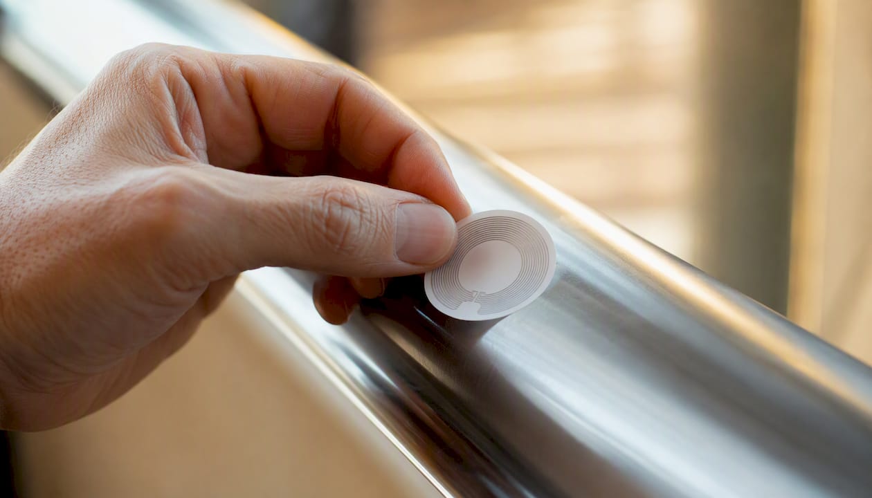 Eine Hand bringt ein Anti-Metall-NFC-Tag an.