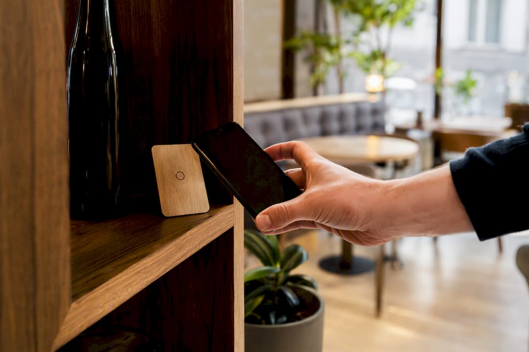 Eine Kundin hält ihr Smartphone an eine NFC-Linkkarte, um kontaktlos Informationen auszutauschen.