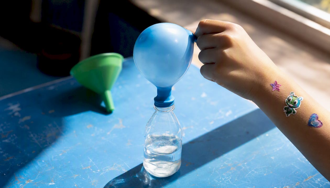 Balloon inflating atop bottle from vinegar and baking soda reaction