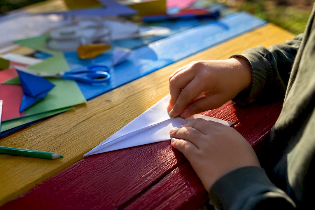 Hands folding dart paper airplane