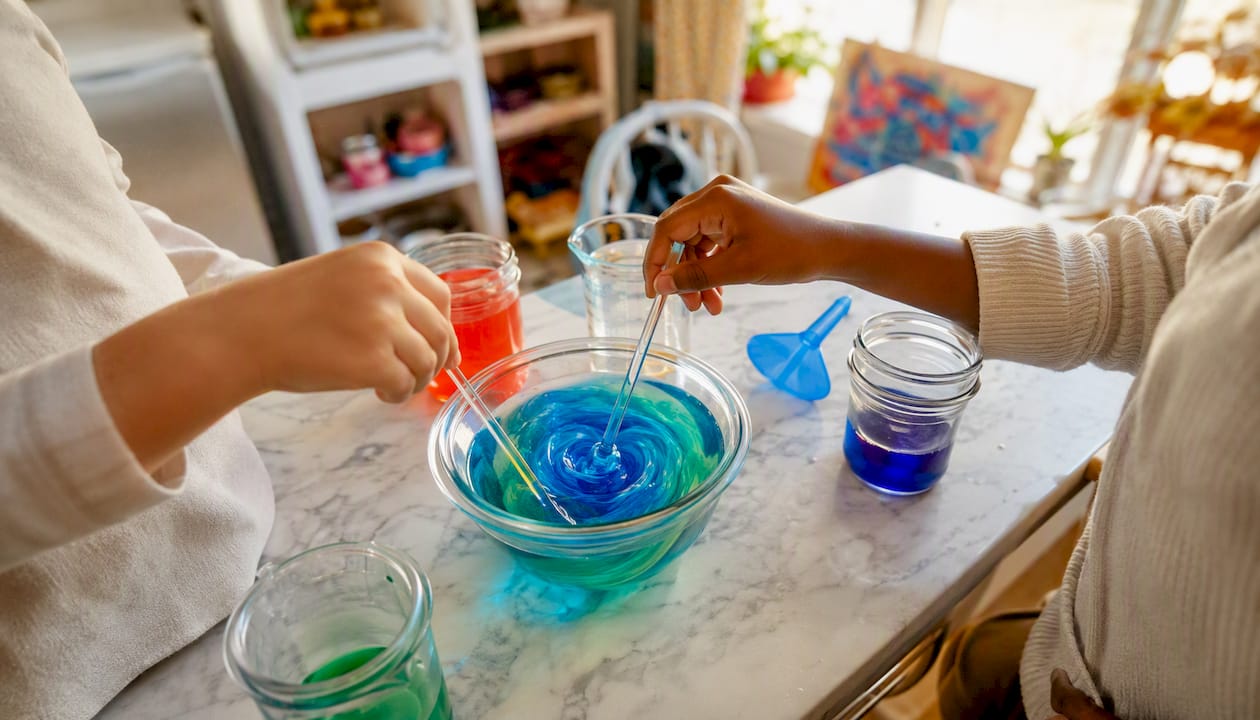 Hands mixing colorful liquids in cups