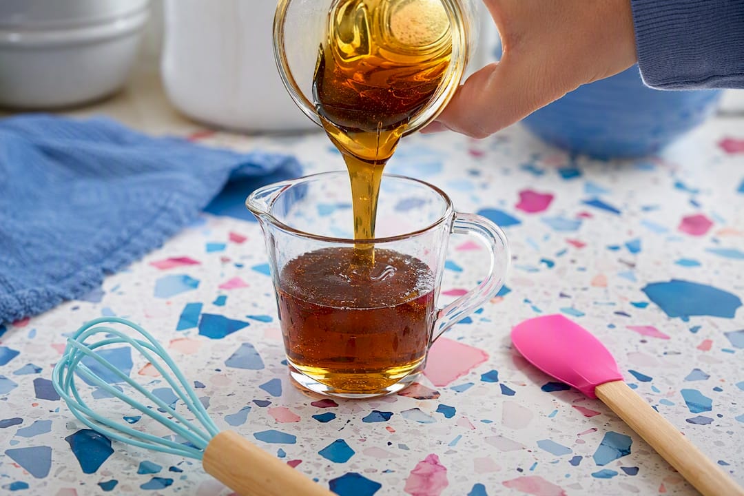 Pouring honey into small liquid measuring cup