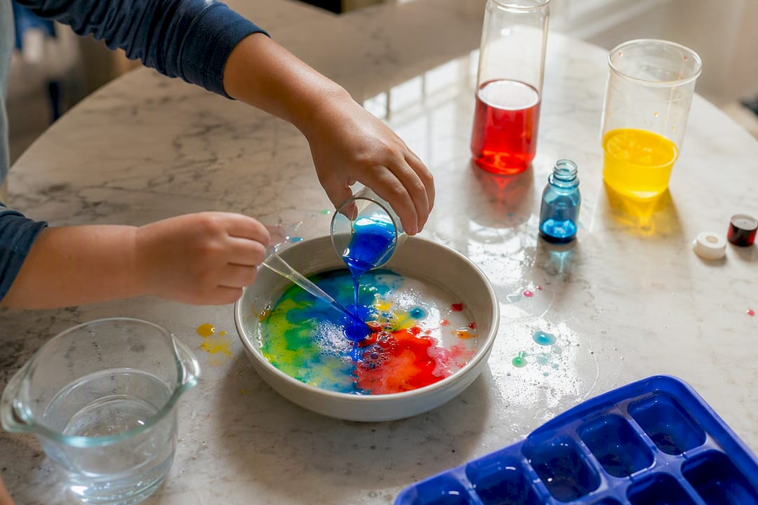 Child hands pouring colored water in quick science experiment