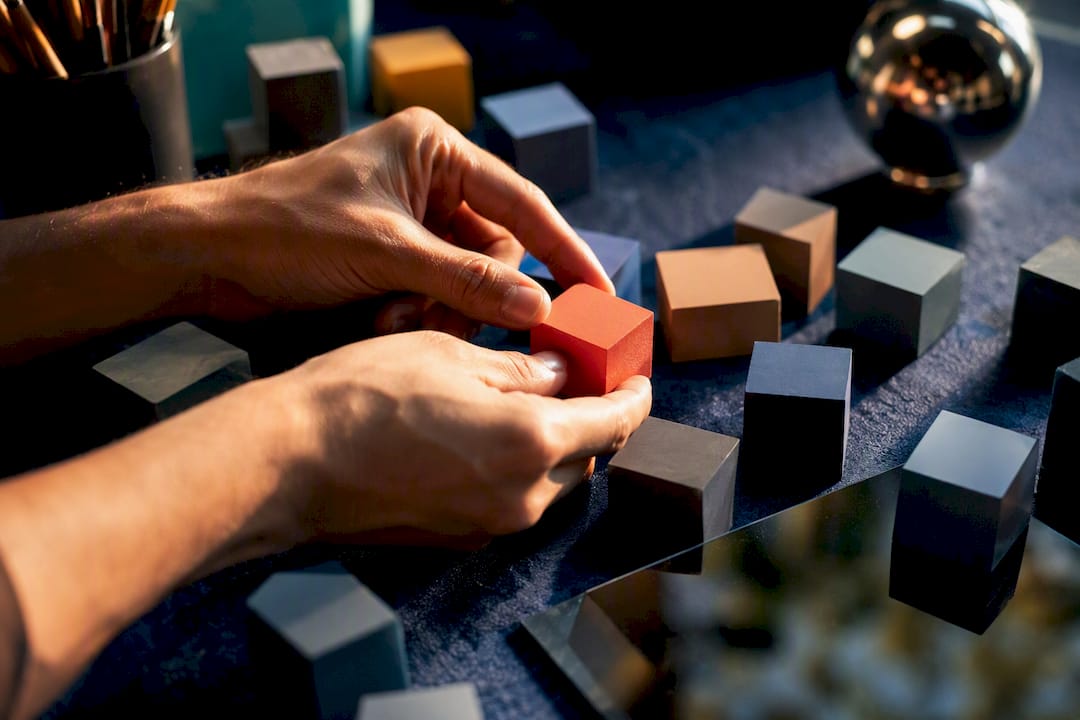 Hands changing one colored cube in grid