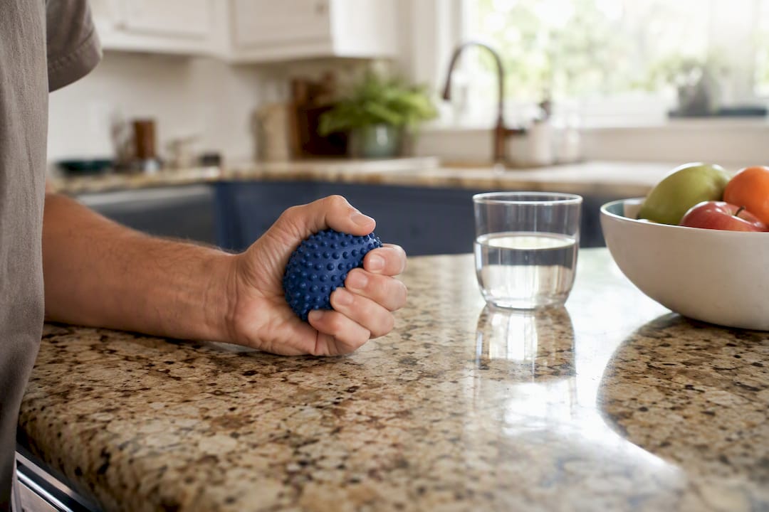 Hand squeezing stress ball in a home kitchen