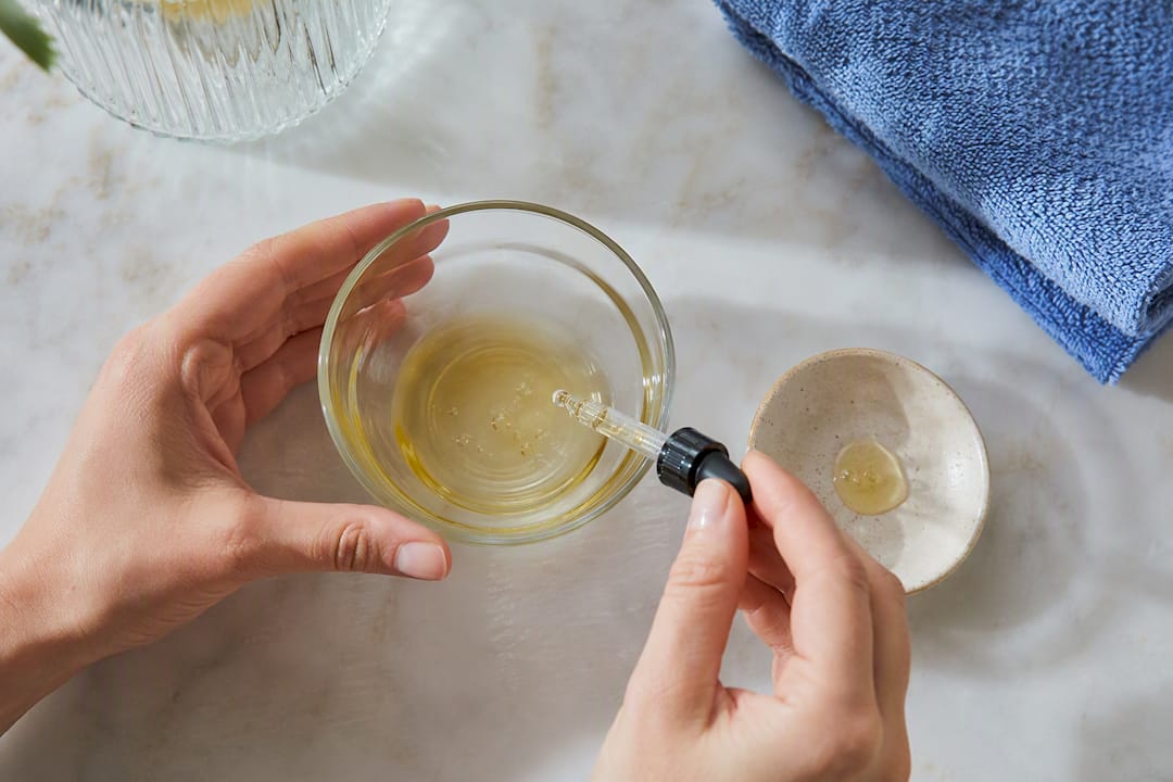 Hands diluting essential oil with carrier oil