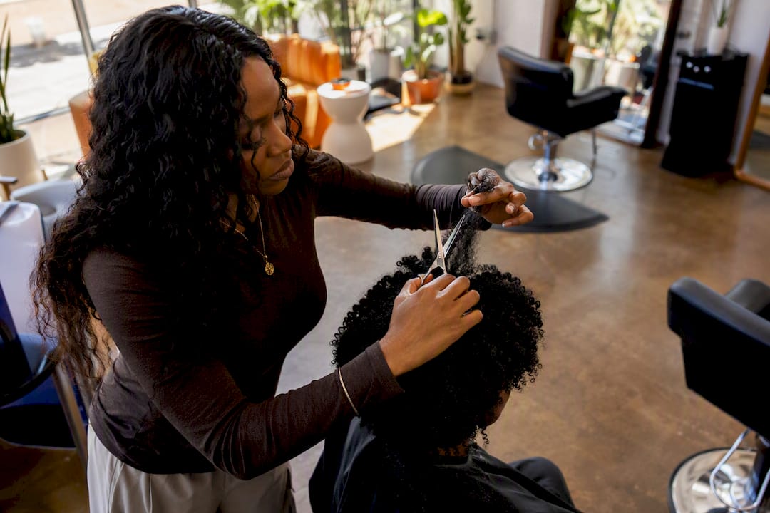 Stylist cutting coily bangs on stretched hair