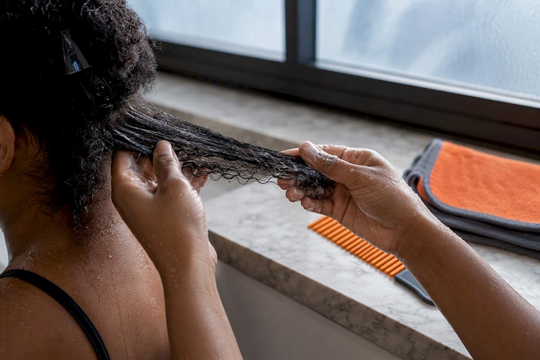 Hands detangling wet natural hair gently