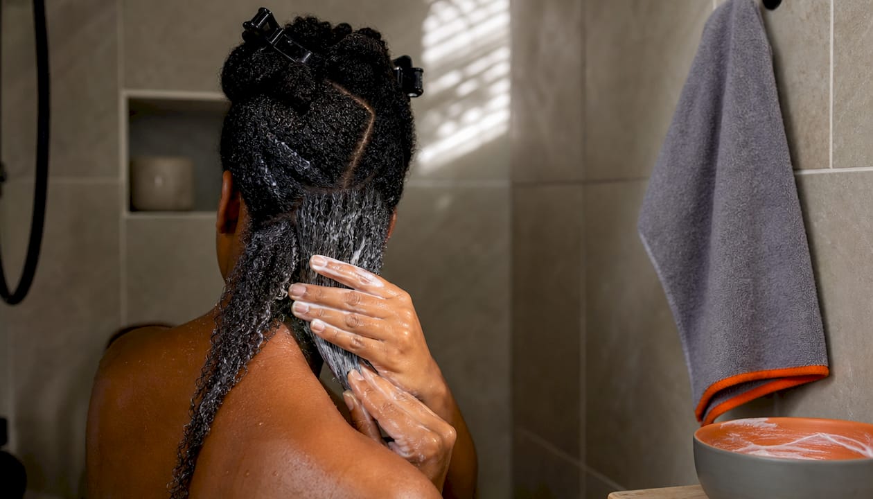 Hands applying conditioner to coiled hair