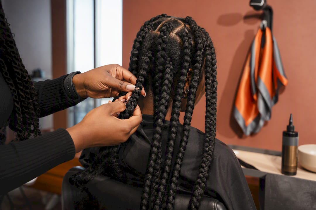 Stylist installing chunky knotless braids