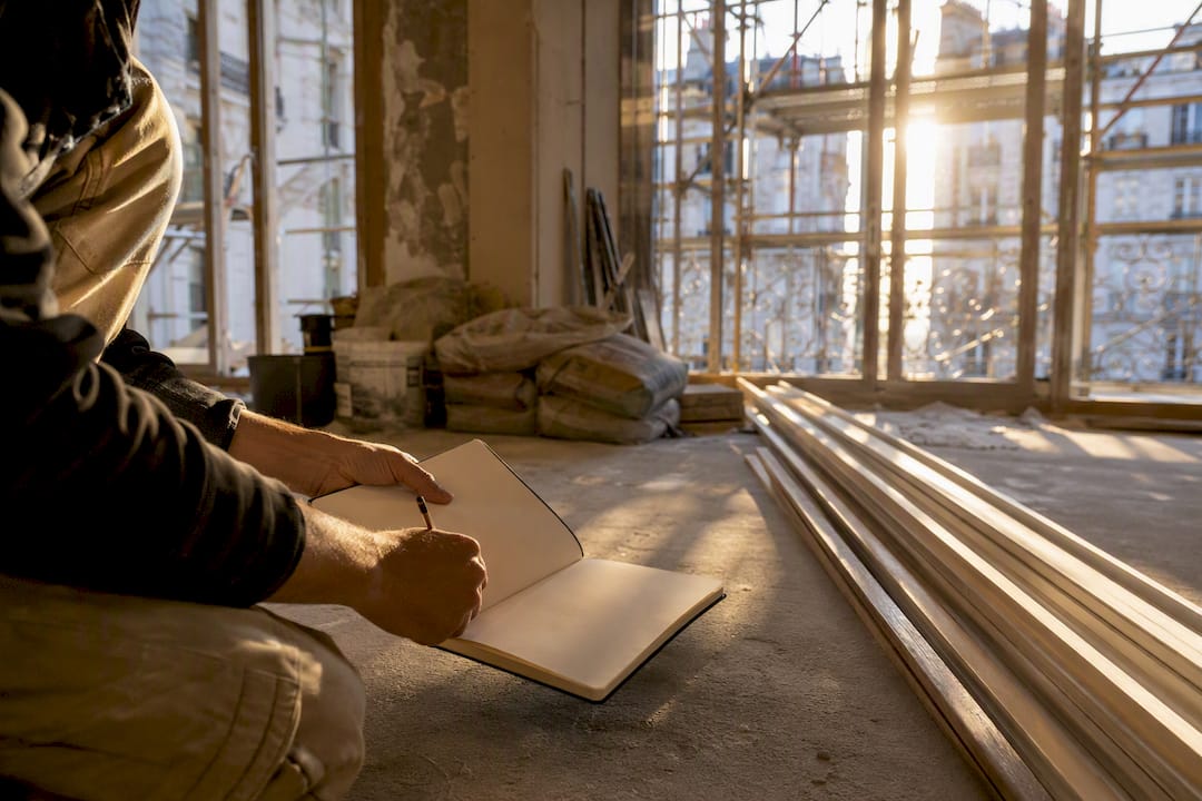 Mains tenant un carnet et un mètre ruban sur un chantier