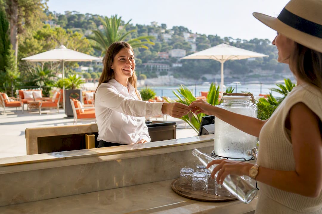 Concierge staff handing keys on sunny hotel terrace