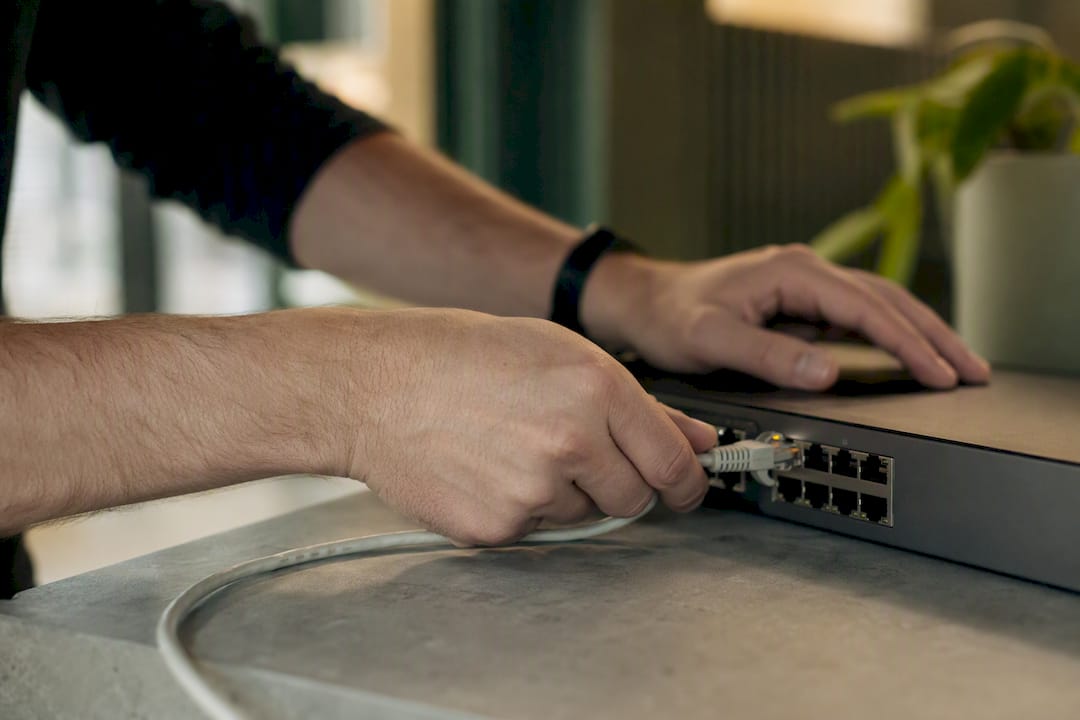 Hands connecting fiber optic cable to network hub