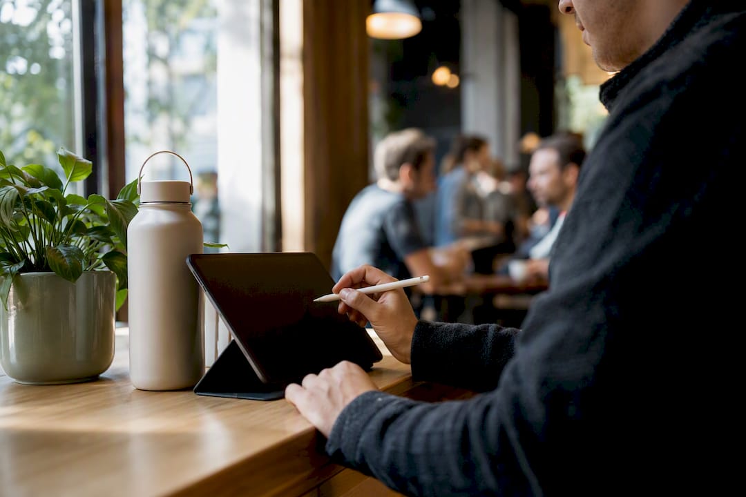 Hands pointing at a tablet with coffee nearby