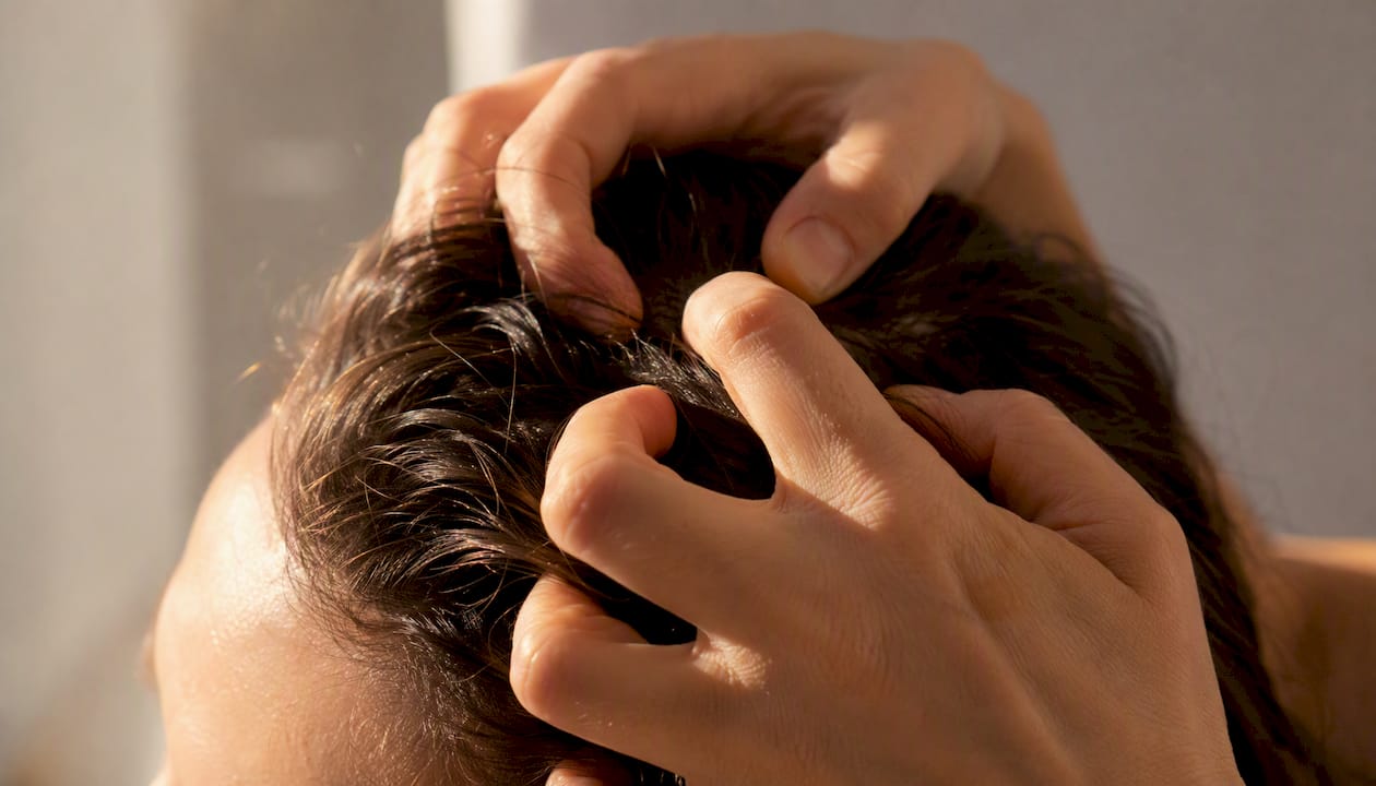 Mani che massaggiano delicatamente il cuoio capelluto, favorendo il rilassamento.