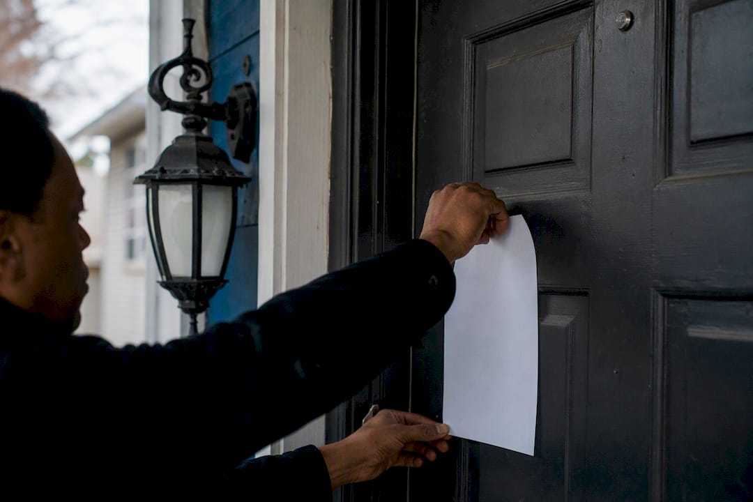 Hand posting eviction notice on rental door