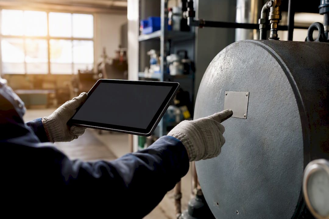 Hands with tablet pointing at asset tag on water heater