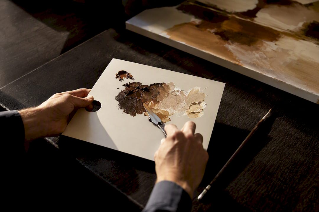 Hands mixing paint colors on palette